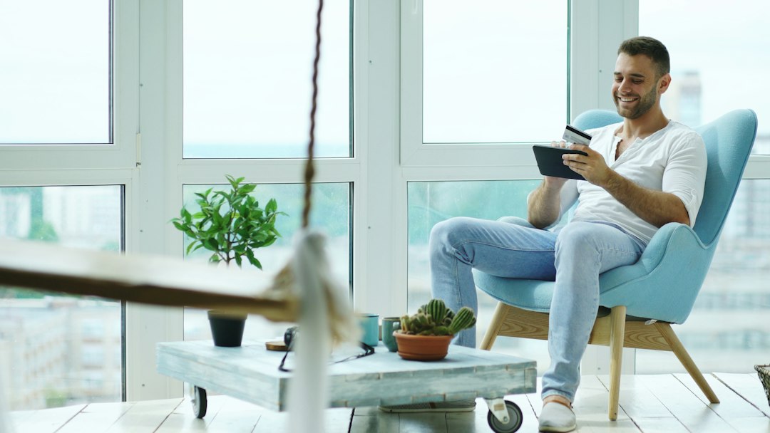 A savvy real estate investor using a tablet while standing inside a modern, well-lit home, symbolizing strategic property management and planning.